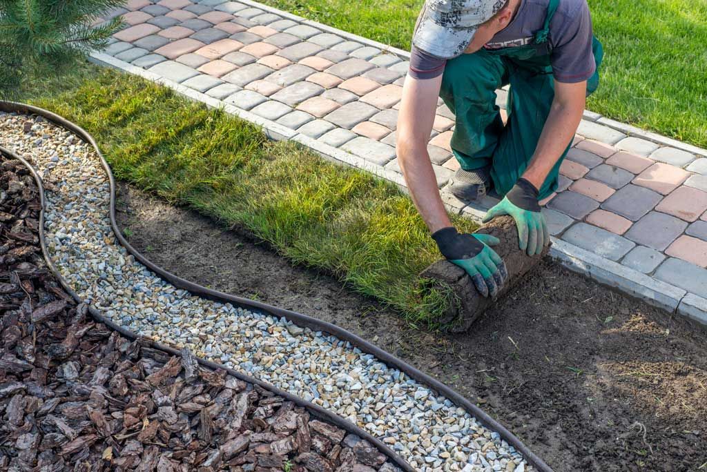 Mitarbeiter der TSG verlegt Rollrasen in einem Garten.